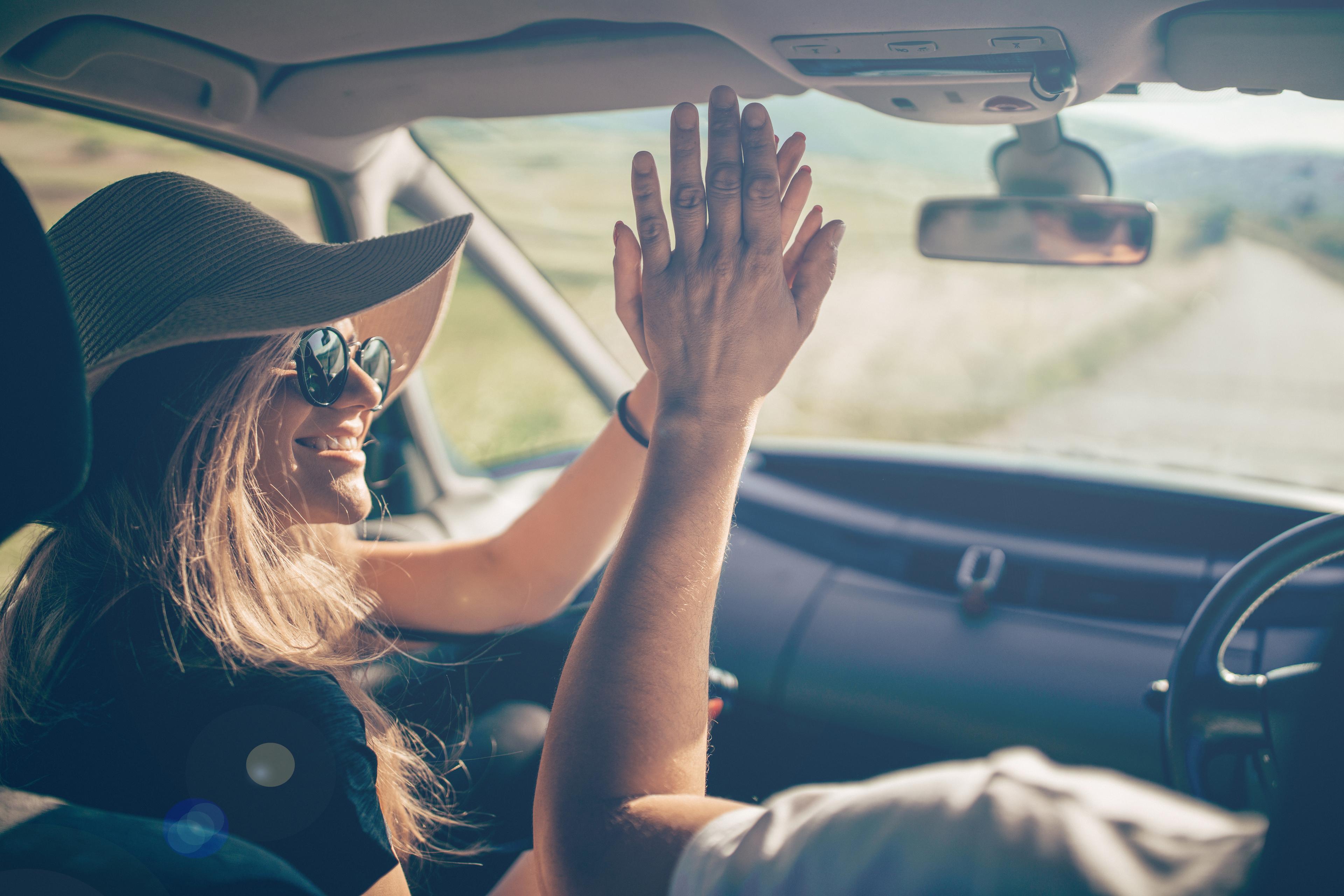 Two people high fiving in a car while driving