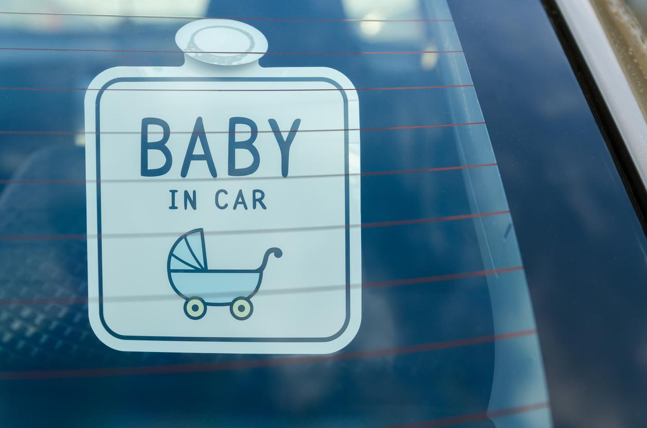 A car window sign reading 'baby in car'