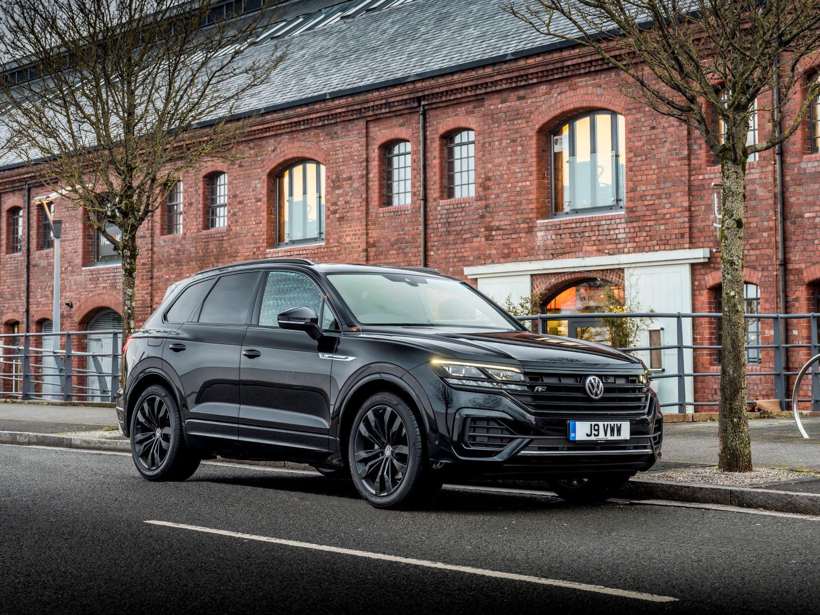 a black volkswagen touareg parked outside a brick house in the UK