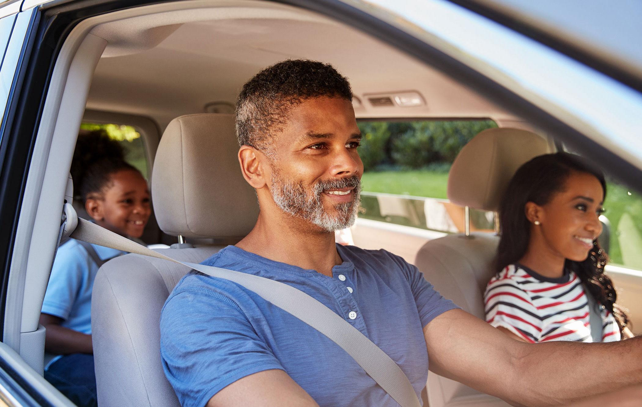 A smiling family sit in a vehicle they secured through used car financing