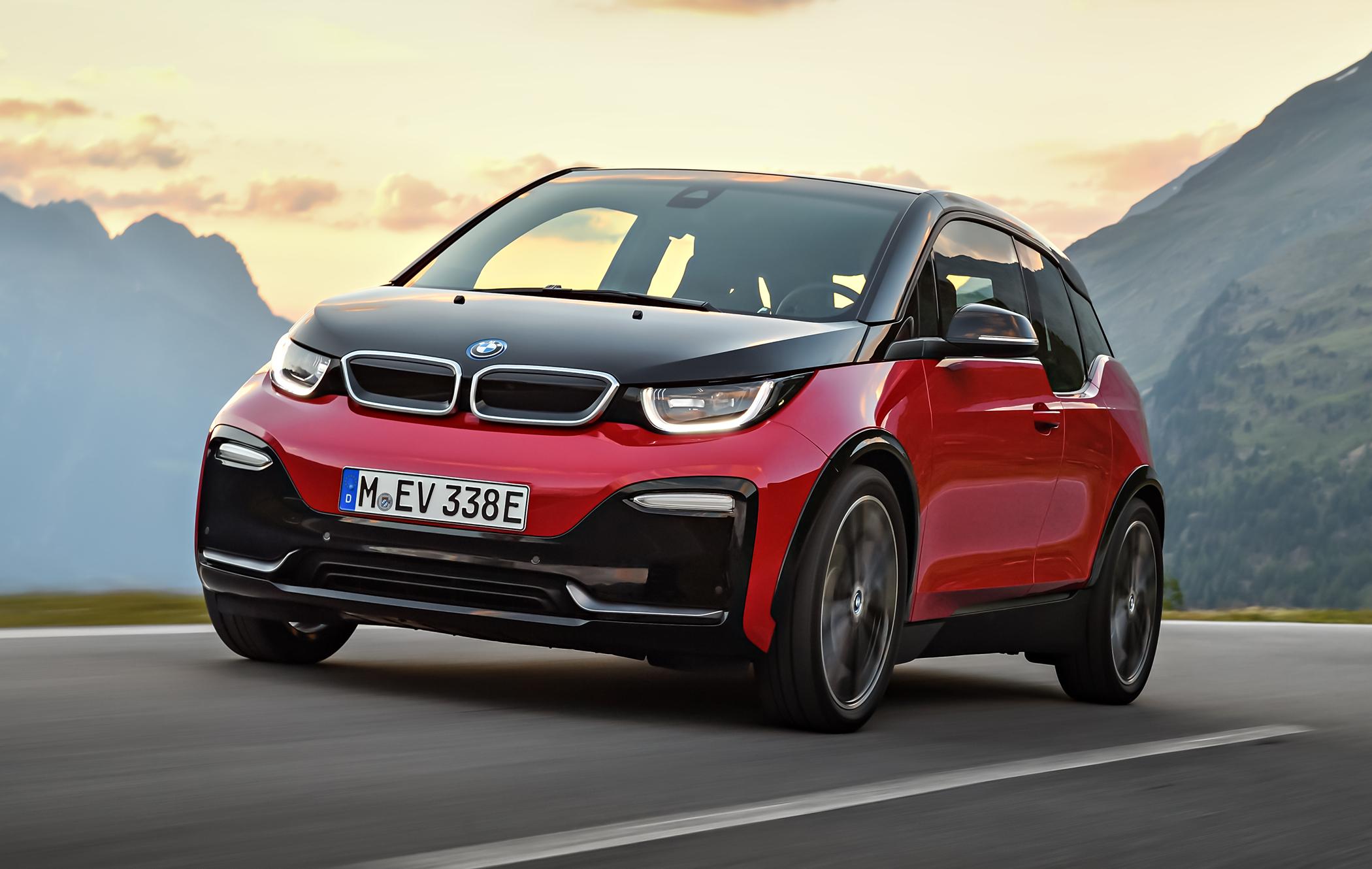 a red and black bmw i3 driving on a mountain road