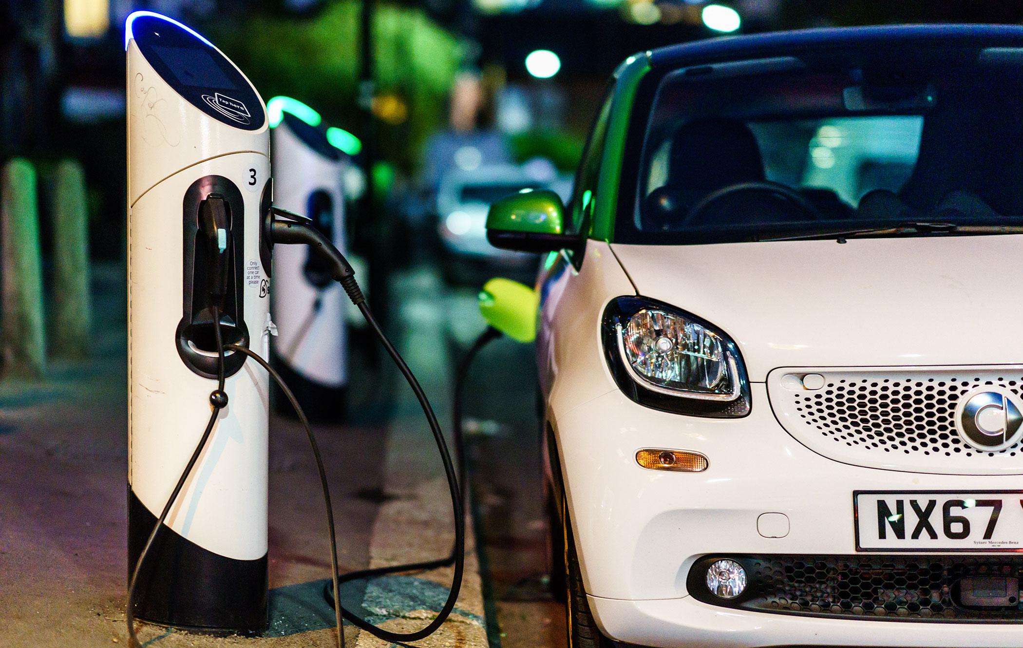 a white smart car parked next to an on-street electric car charger