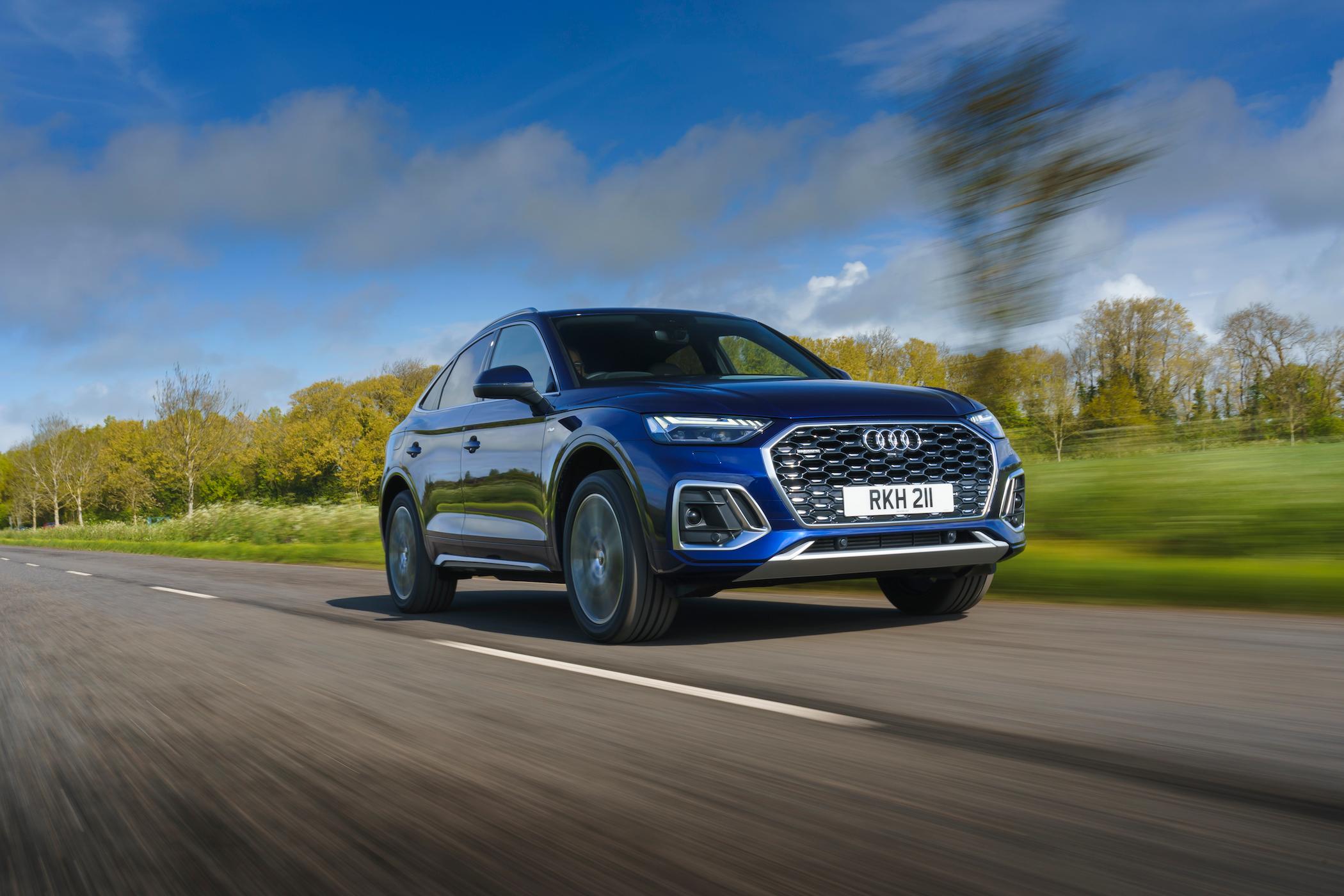 a dark blue audi q5 driving on a country road