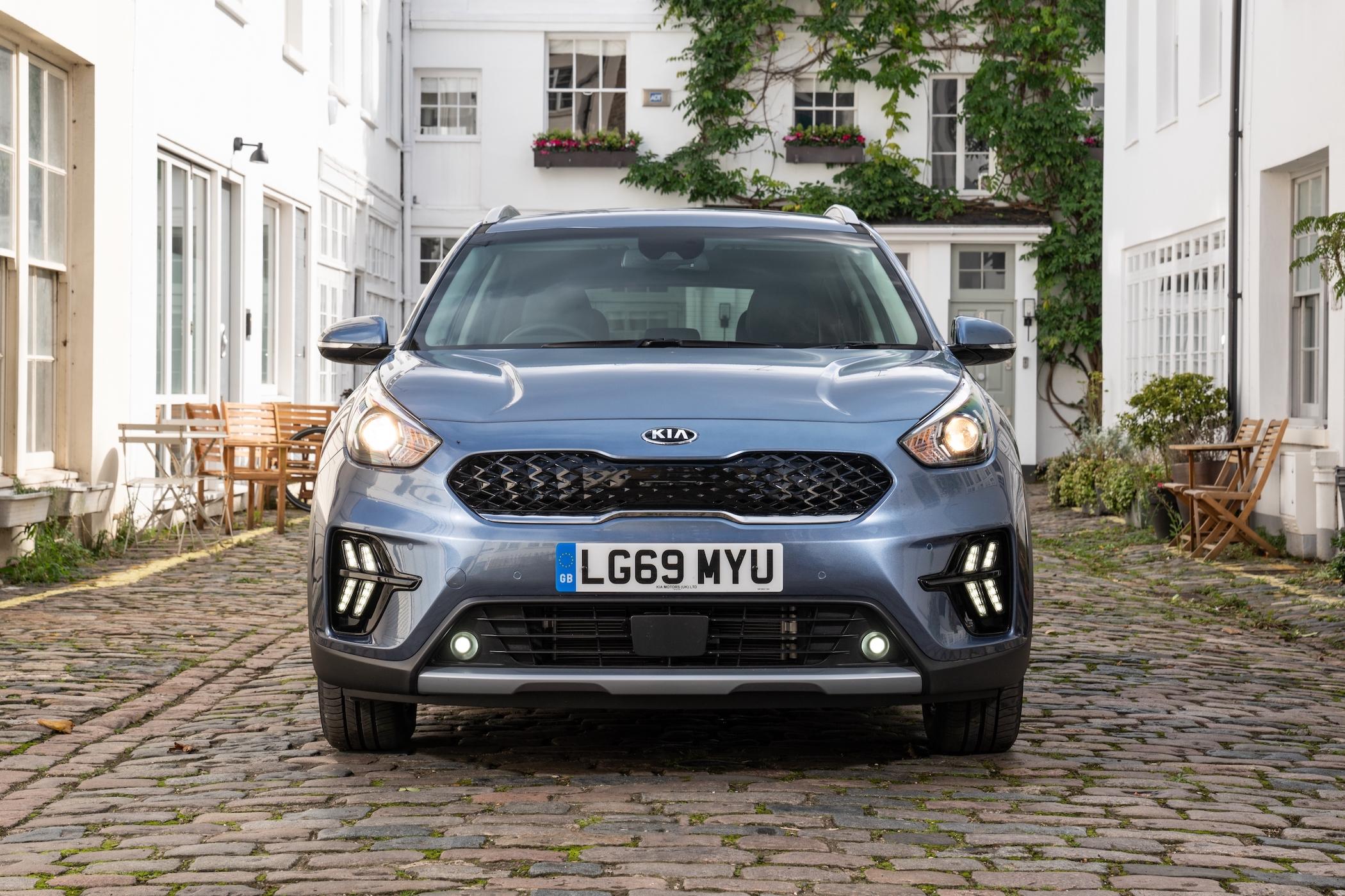 a blue kia niro parked on a quiet, cobbled street in london