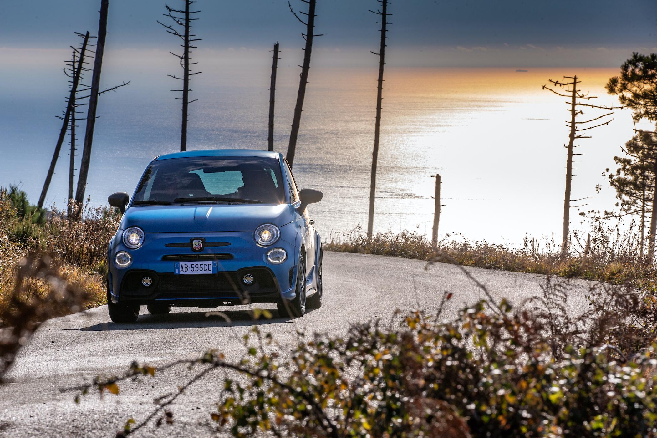 A blue Abarth parked by the sea