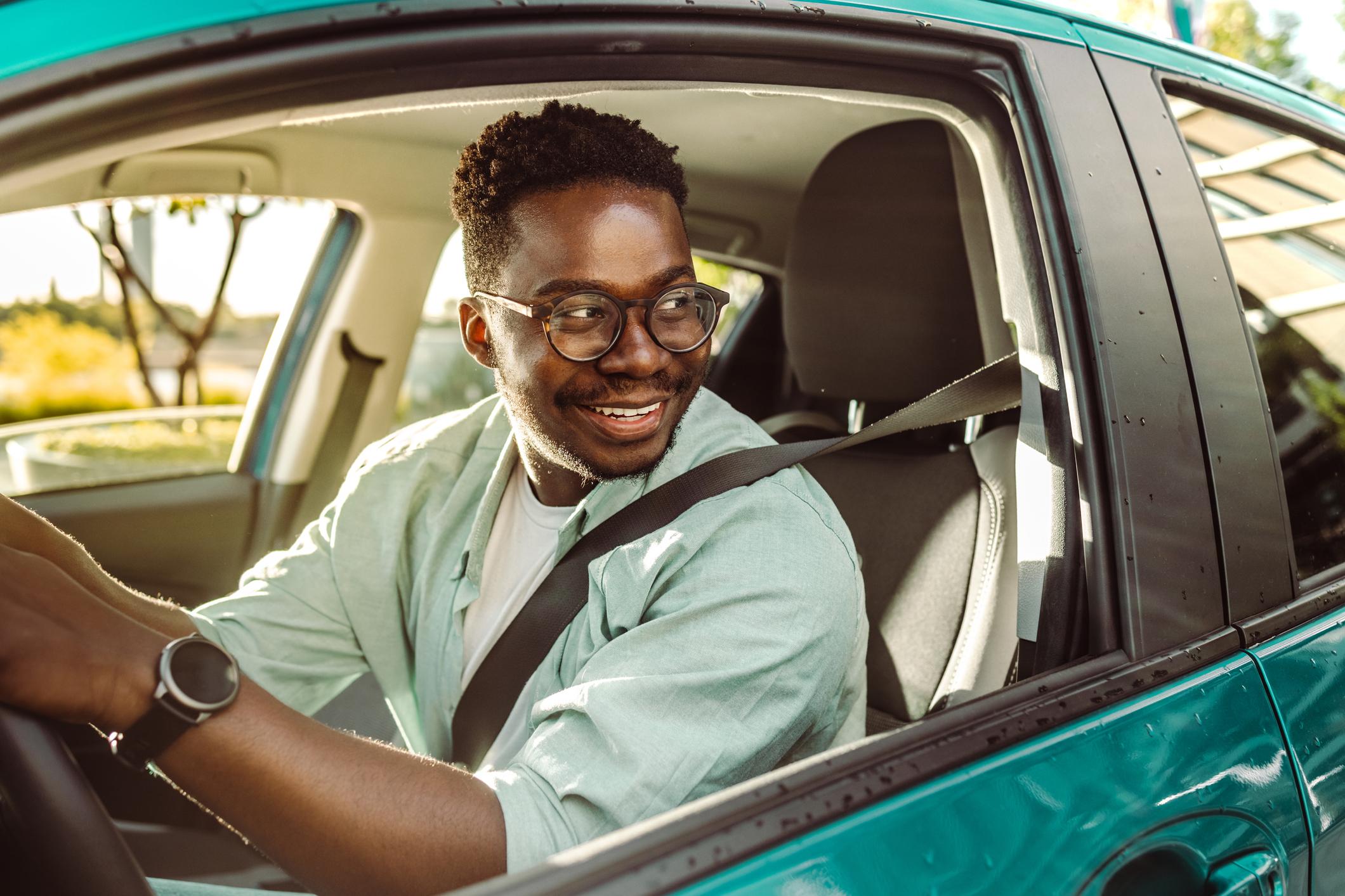 A man driving a blue car while smiling