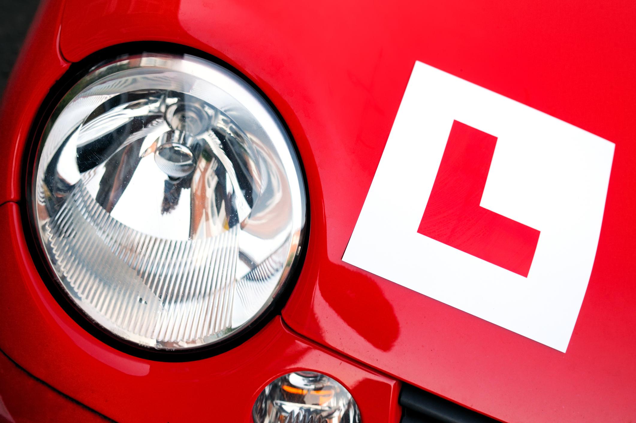 A red 'L' plate on the front of a red Fiat car
