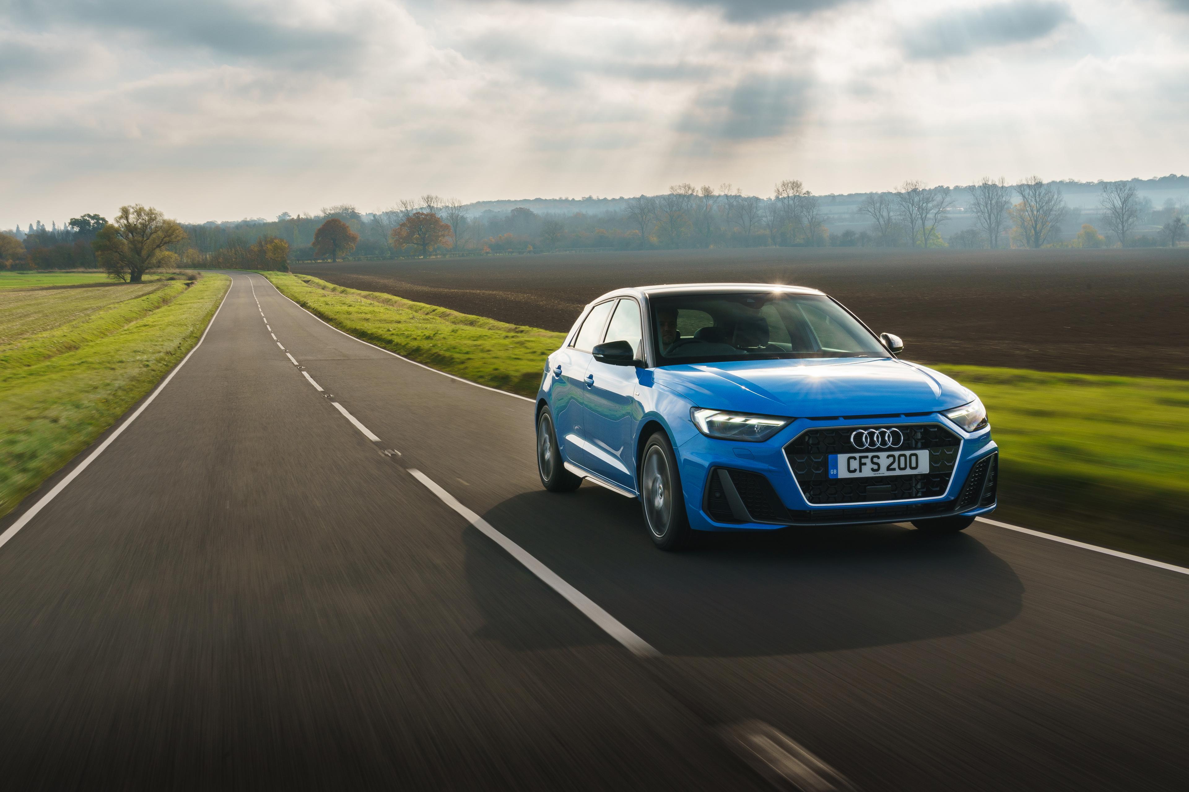 A blue Audi A1 driving on an empty road