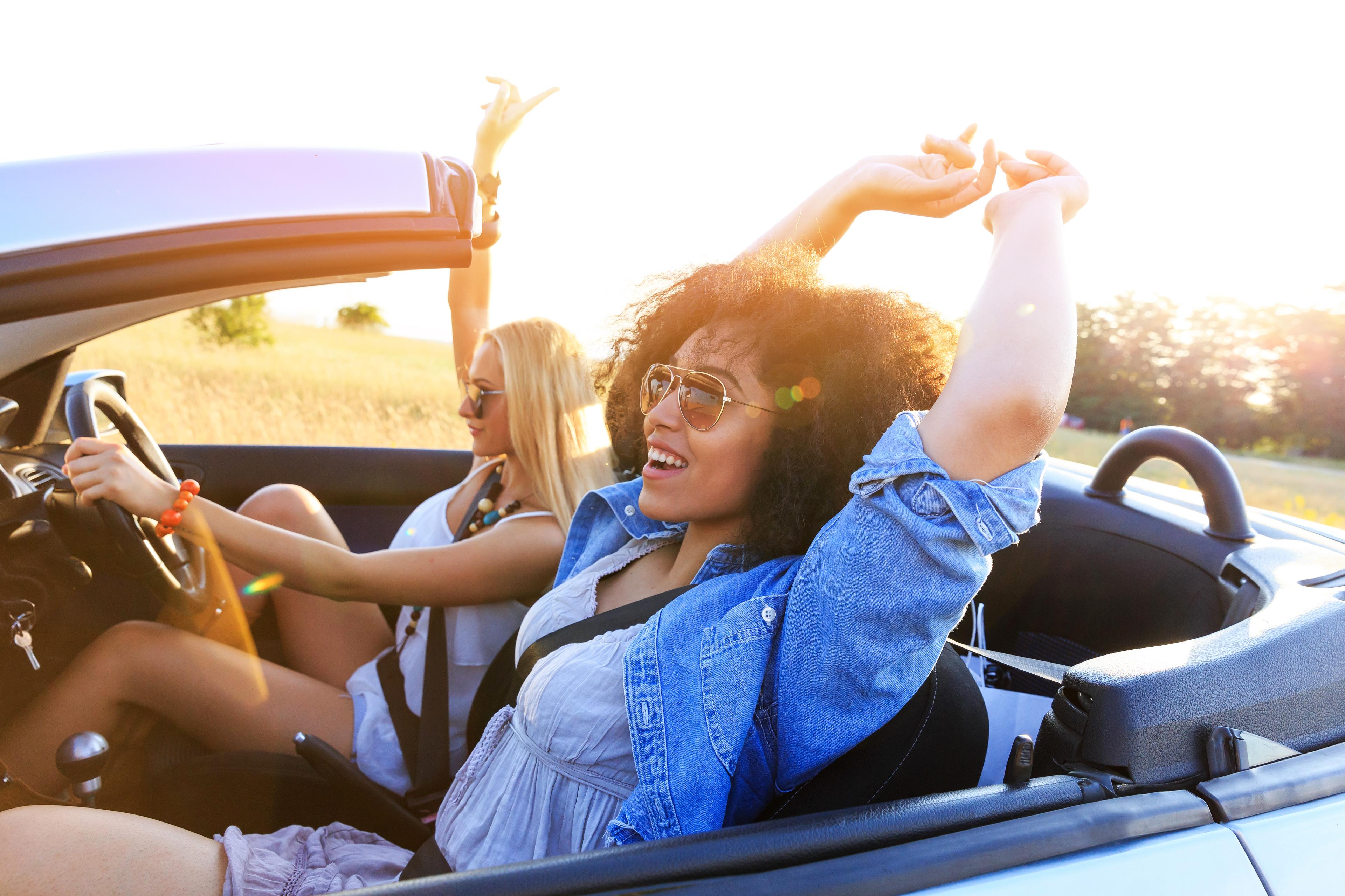 Two women looking happy in a convertible car